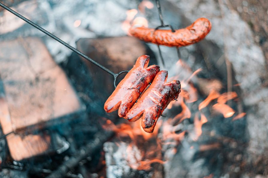 Alt-text:”Würstchen am Stock über Feuer